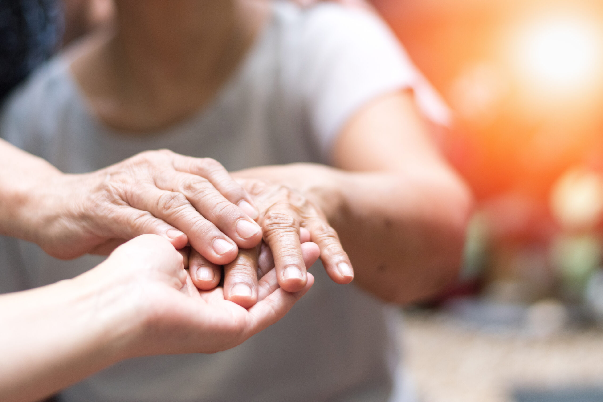 Caregiver, carer hand holding elder hand woman in hospice care.