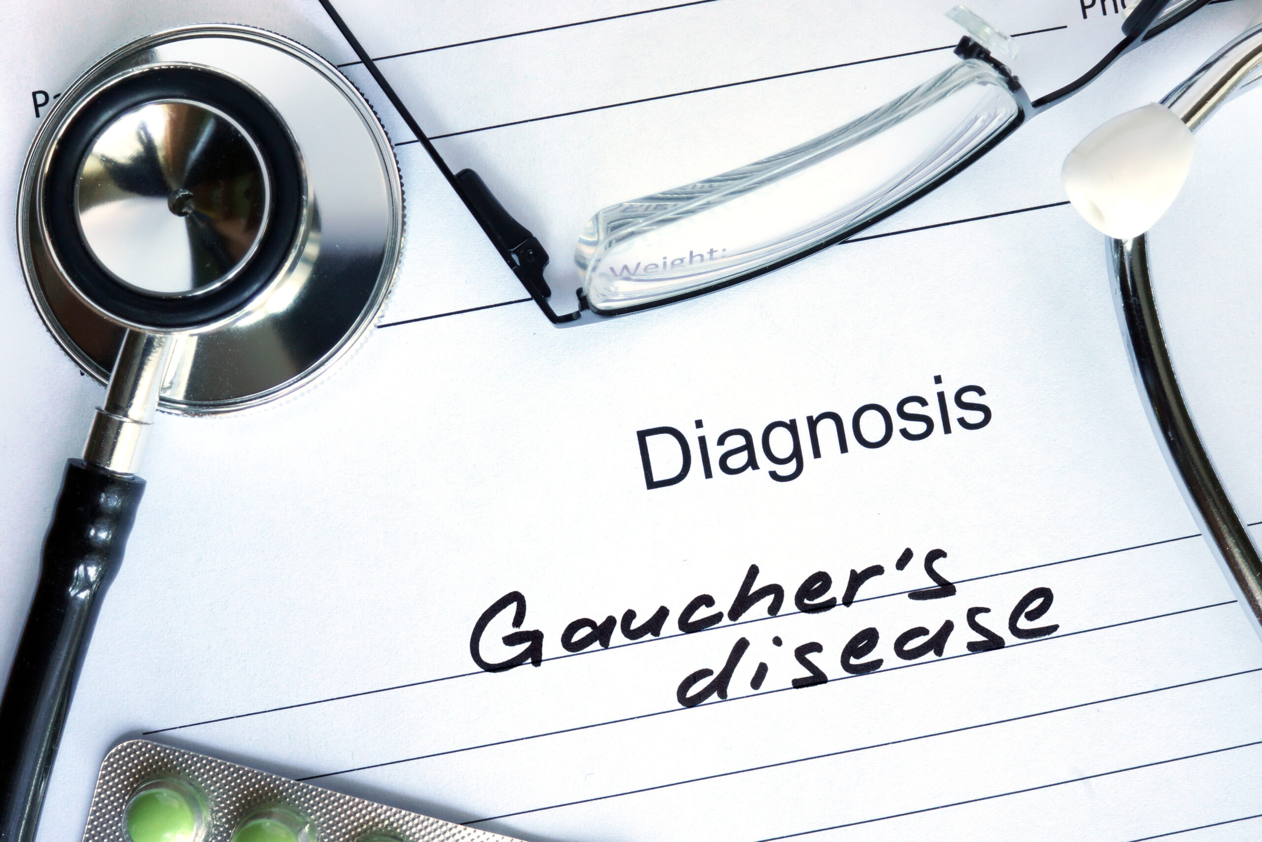 Diagnosis Gauchers disease and tablets on a wooden table.