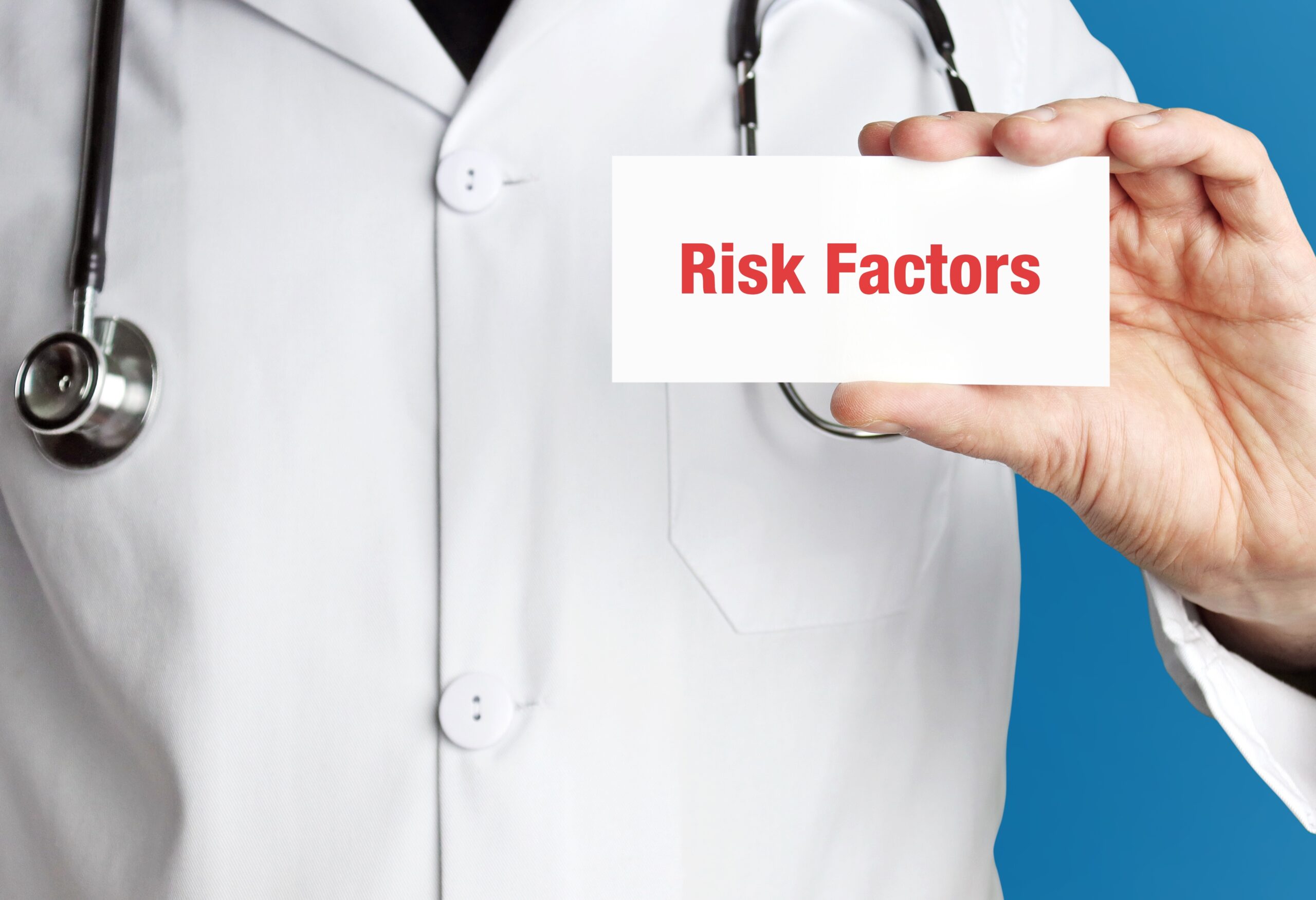 Risk Factors. Doctor in smock holds up business card. The term Risk Factors is in the sign. Symbol of disease, health, medicine