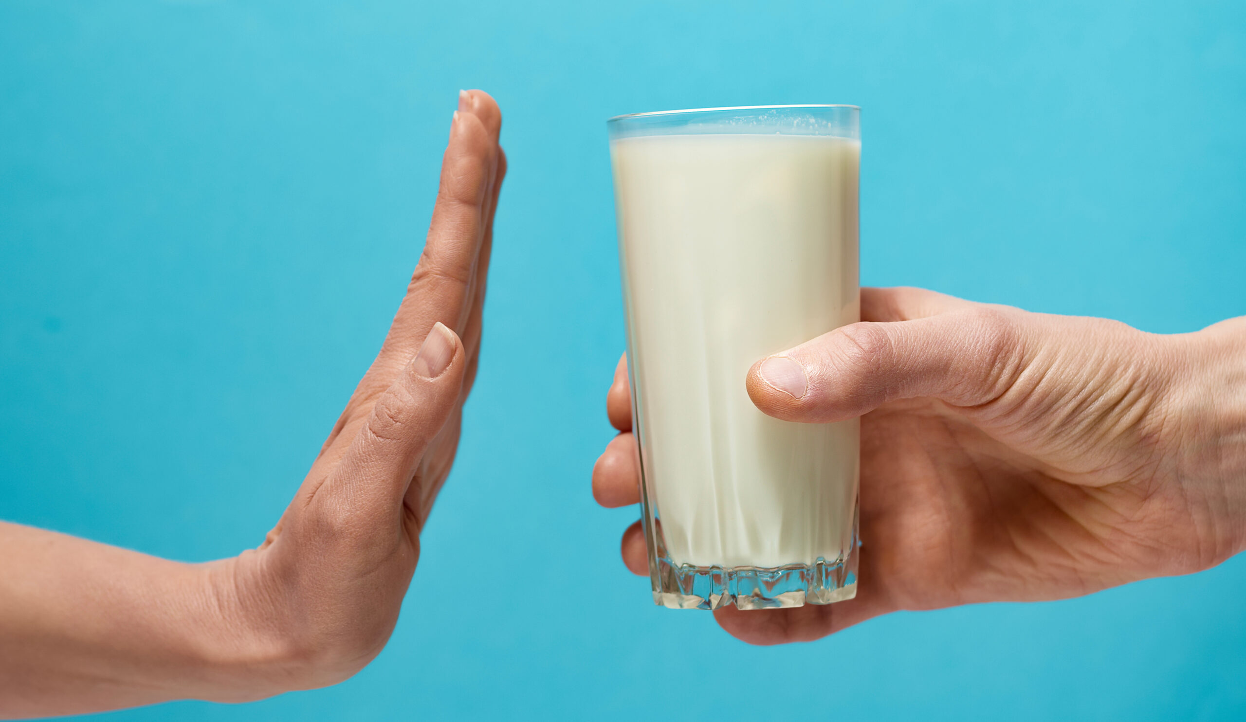 Lactose intolerance. Glass of milk and hand showing stop.